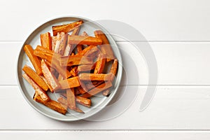 Plate with deliciously cooked sweet potatoes, rosemary, sauce and spices, herbs on a wooden