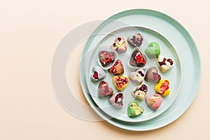 Plate with different chocolate on colored background. Assortment of fine chocolates top view vith copy space Health and