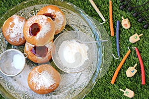 Plate of doughnuts and Hanukkah items outside on a grass background