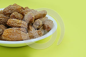 Plate of Dried date fruits or Phoenix dactylifera on a yellowbackground