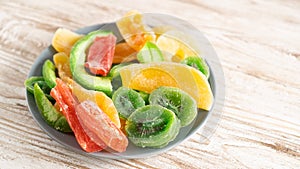 Plate of dried fruits on a wooden table. kiwi, mango, papaya, melon, pineapple. do not affects blood sugar levels