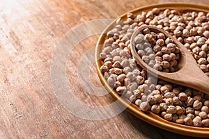 Plate with dry chickpeas and spoon on table