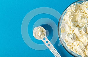 Plate with dry milk mixture enriched with vitamins, minerals and bifidobacteria on a blue background. Copy space for