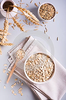 A plate with dry oatmeal and ears of oats on a gray background. Top and vertical view