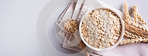 A plate with dry oatmeal and ears of oats on a gray background. Top view web banner