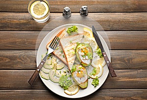 Plate with eggs baked in avocado and fresh vegetables on wooden table