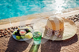 Plate with exotic fruits and drink by swimming pool. All inclusive