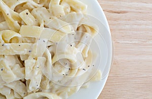 Plate of fettuccine alfredo on wood table top close view