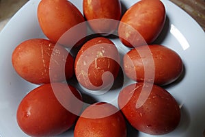 Plate is filled with numerous red Easter eggs with natural red-brown color and textured eggshells photo