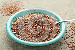 Plate with flax seeds on grey background