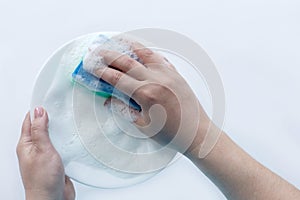 Plate in foam in hand, washing dishes