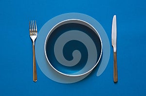 Color plate fork and knife  on blue background.