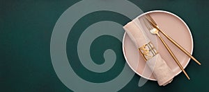 Plate with fork and knife. Mockup with empty space. Gold cutlery, dark green background. Top view. Celebration place setting,