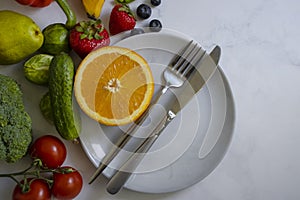 Plate fork knife vegetables organic fruits on a light background