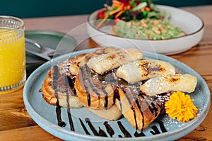 A plate of french toast with bananas and syrup on top