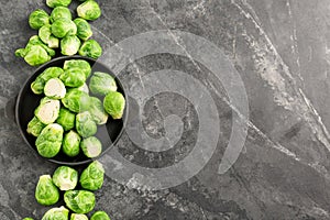 Plate with fresh brussels sprouts on grey background, top view