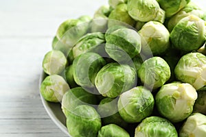 Plate with fresh Brussels sprouts on wooden background