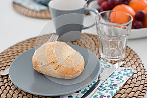 Plate with fresh crusty bread and glass of juice on grey plate