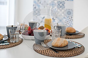 Plate with fresh crusty bread and glass of juice on grey plate