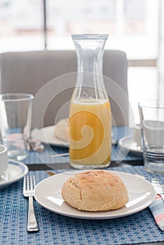 Plate with fresh crusty bread and glass of juice on white plate