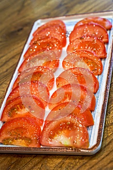 A plate of fresh and delicious raw tomato slices in white sugar