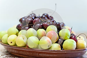 A plate with a fresh fruits and berries. Sweet cherries, apricots, peaches and nectarines