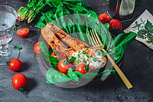 A plate with fresh green raw spinach and fried wild salmon, tomatoes and cream cheese sauce