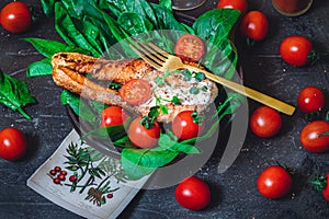 A plate with fresh green raw spinach and fried wild salmon, tomatoes and cream cheese sauce