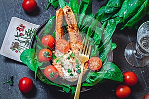 A plate with fresh green raw spinach and fried wild salmon, tomatoes and cream cheese sauce