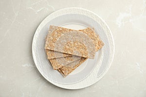 Plate with fresh rye crispbreads on light grey marble table, top view