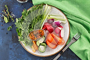 Plate with fresh vegetable sliced salad with cucumber, tomato, pepper and dill, parsley on blue background