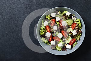 Plate with fresh vegetables salad on a black background.
