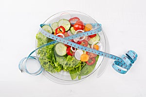 Plate with fresh vegetables salad and measured tape isolated on