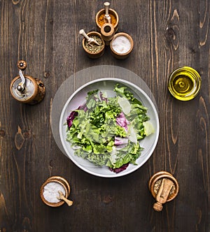 Plate of fresh vegetarian salad with herbs, butter and herbs wooden rustic background top view close up
