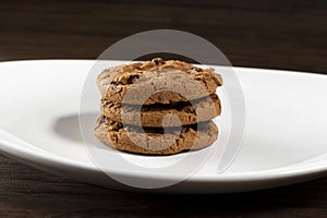 Plate of freshly baked chocolate chip cookies. Wooden background, selective focus