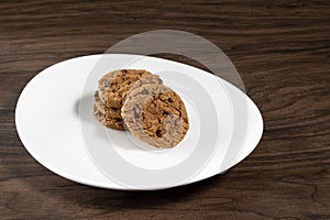 Plate of freshly baked chocolate chip cookies. Wooden background, selective focus