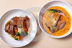 Plate with fried chicken and carrot-potato puree and plate of beef ribs in barbecue sauce with vegetables