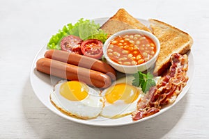 plate of fried eggs with bacon  beans  sausages  toasts and tomatoes