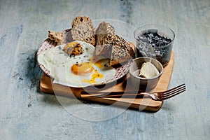 Plate of fried eggs with seed bread, black salt and butter, breackfast toast