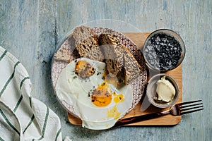 Plate of fried eggs with seed bread, black salt and butter, breackfast toast