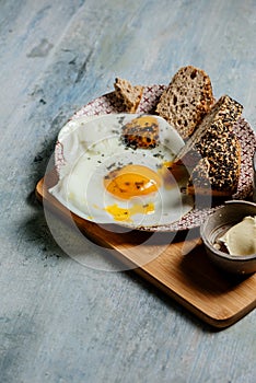 Plate of fried eggs with seed bread, black salt and butter, breackfast toast