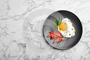 Plate with fried sunny side up egg and tomato on marble background, top view. photo