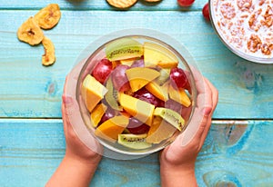 Plate with fruit salad in the hands of the child