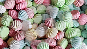 A plate full of colorful meringue cookies on a white background.