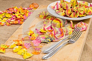 Plate full of colorful ravioli pasta two forks on a wooden board and canvas