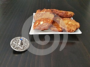 A plate full of hannukah potato latkes fritters with a silver dreidel on a wooden table