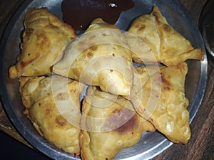 A plate full of homemade delicious Indian snack- Samosa, served with green chutney