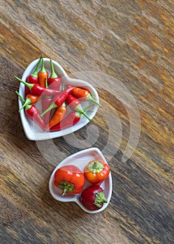 Plate full of hot red peppers on wooden background with copy space