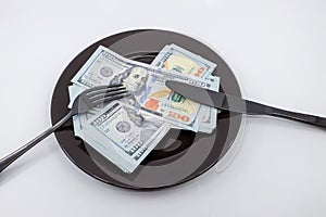 Plate full hundreds of dollar bills with fork and knife. Concept of prosperity and abundance. Full plate concept. Concept of dine