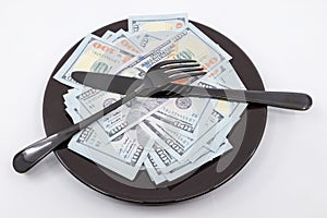 Plate full hundreds of dollar bills with fork and knife. Concept of prosperity and abundance. Full plate concept. Copy space